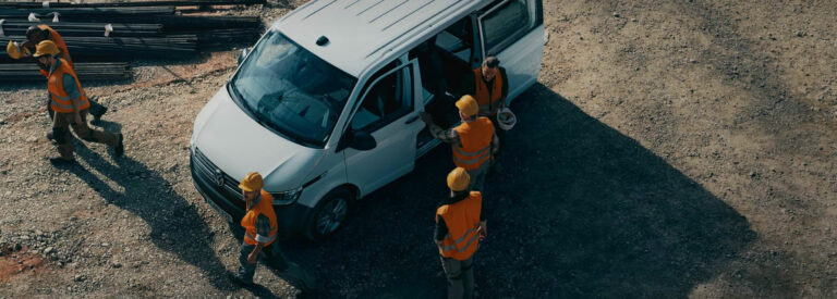 Volkswagen T6.1 Kastenwagen, Luftaufnahme auf einer Baustelle mit Bauarbeitern in orangenen Warnwesten.